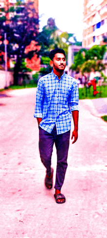 a young man in a blue plaid shirt walks down a street
