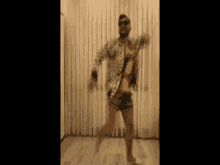 a man wearing sunglasses and shorts is dancing in a room