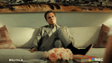 a man in a suit is sitting on a couch with his feet up and the hashtag #suitsla