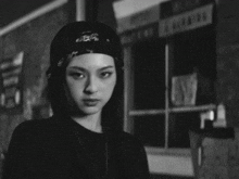 a black and white photo of a woman wearing a bandana and hat