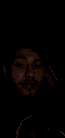 a man is smoking a cigarette in the dark with a light on his face