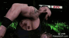 a wrestler is squatting in the middle of a wrestling ring .