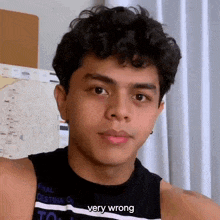 a young man with curly hair is wearing a black tank top with the words `` very wrong '' on it .