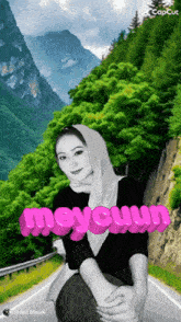 a woman wearing a hijab is sitting on the side of a road with the word mey cuun written in pink
