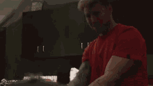a man in a red shirt is standing in a kitchen with black cabinets