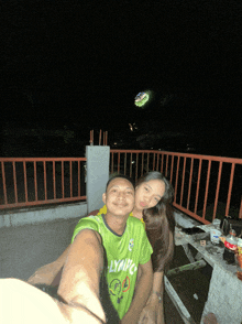 a man wearing a green shirt that says lyng on it poses with a woman