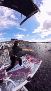 a woman is jumping over a sign that says red bull diving