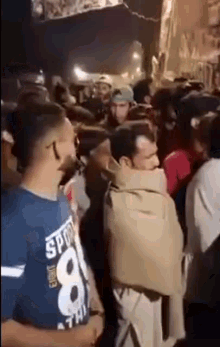 a man wrapped in a blanket is standing in a crowd of people at a party .