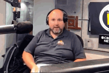 a man wearing headphones is sitting in front of a microphone in front of a sign that says cb news