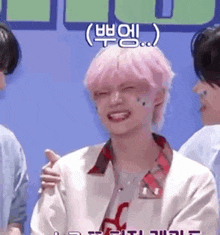 a young man with pink hair is smiling and laughing while standing next to a group of people .