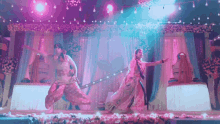 a man and a woman are dancing on a stage with flowers in the background .