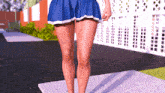 a woman in a short blue skirt is walking down a sidewalk