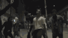 a blurry photo of a group of people standing on a street at night .