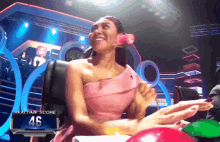 a woman in a pink dress is sitting in front of a scoreboard with the number 46 on it