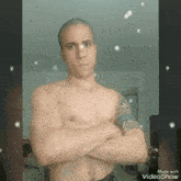 a shirtless man with a tattoo on his arm is standing with his arms crossed in a video made with videoshow