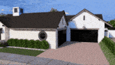 a white house with a black garage and a round window