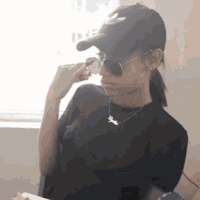 a woman wearing a hat and sunglasses has a necklace that says " sydney " on it