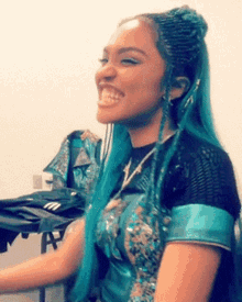 a woman with blue hair is smiling and wearing a black shirt .