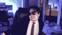 a man in a suit and tie is wearing sunglasses and smiling