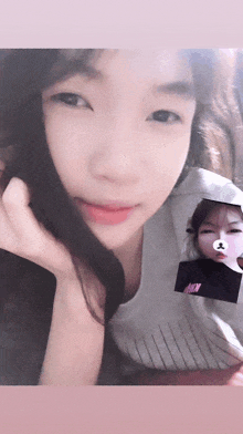 a girl is holding a picture of herself with a bear on her nose