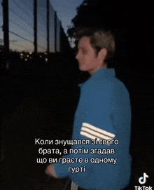 a man in a blue jacket is standing in front of a fence with a tiktok watermark on the bottom