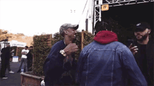 a man in a red hoodie is talking to another man in a blue jacket