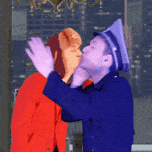 a man in a blue hat is kissing a woman in a red jacket