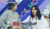 two girls are sitting in front of a blue sign that says idol house
