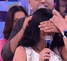 a woman is covering her eyes while holding a microphone in front of her face .