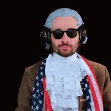 a man wearing a wig and sunglasses is wearing an american flag scarf around his neck