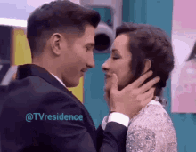 a man and woman are touching each other 's faces with the words @tvresidence visible in the corner .