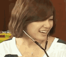 a woman is smiling while wearing a headset and a necklace .