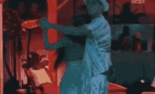 a man in a hat is dancing on a stage in front of a crowd of people .