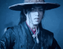 a man wearing a straw hat and a black jacket is standing in the rain .