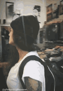 a woman wearing a black beanie and a white shirt with a backpack