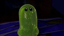 a green pickle with a sad face is sitting on a blue blanket