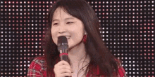 a young woman is holding a microphone and smiling in front of a wall of lights .