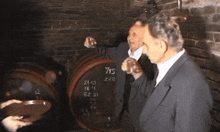 two men are standing in front of a barrel that says 715 on it