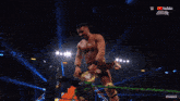 a shirtless wrestler is holding a wrestling championship belt over his head in front of a crowd sponsored by youtube