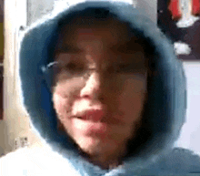 a close up of a person wearing a hoodie and glasses .