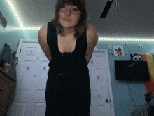 a woman in a black tank top is standing in a room with a skull on the wall