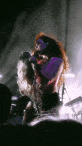 a woman with red hair singing into a microphone on stage