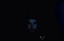 a man is looking at a computer screen in the dark with headphones on .
