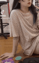 a girl with blue hair is sitting on the floor with tiktok written on the bottom right