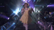 a girl in a yellow dress is walking through a tunnel