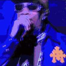 a pixelated image of a man wearing sunglasses and a blue jacket with the letter t on it