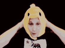 a man wearing a yellow chicken hat and a black shirt with a star on it