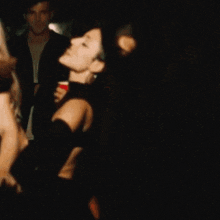 a woman in a black dress is dancing in a dark room