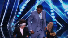 a man in a suit is dancing on a stage with two other people