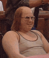 a bald man wearing sunglasses and a tank top is smiling .